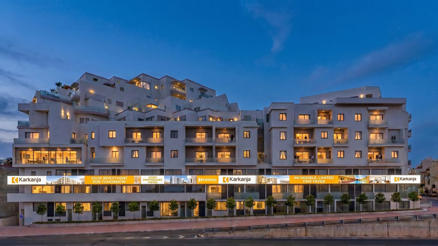 The same facade at dusk, apartments lit and the campaign illuminated